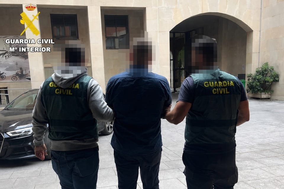 Civil Guard officers patrol Passeig de Gràcia, a busy street in Barcelona, with luxury shops and historic buildings.