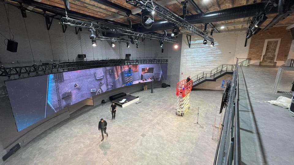 Interior view of Espai Diagonal, showing a large, modern event space with a high ceiling and a large LED screen.