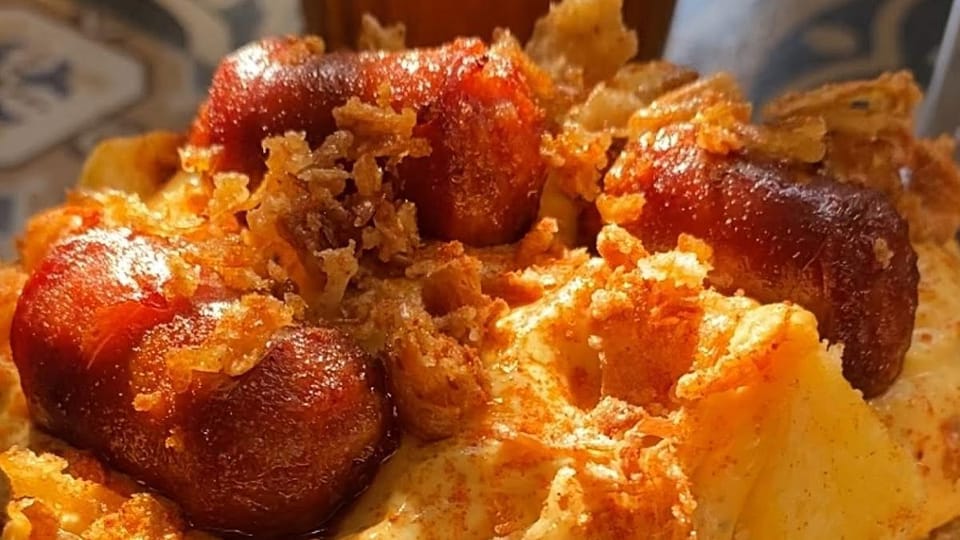 A plate of 'Patatas Bárbaras' from Le Petit, featuring crispy potatoes, a special sauce, chistorra, crispy onion, and Parmesa