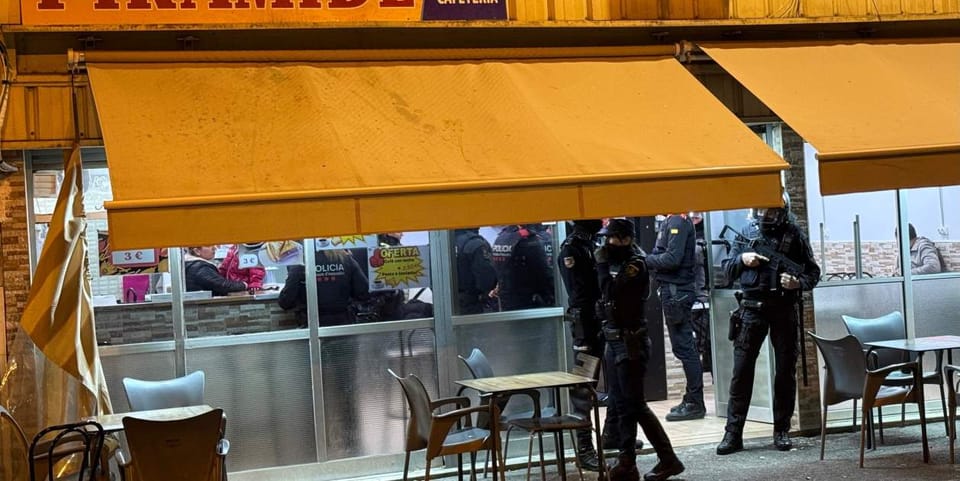 Police officers conducting an operation in a residential neighbourhood, possibly La Mina, with police vehicles visible.