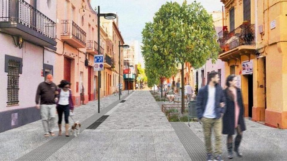 A busy street in Barcelona's Nou Barris district with cars, pedestrians, and apartment buildings.