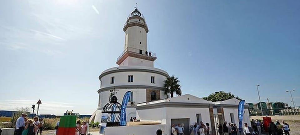 Llobregat Lighthouse at the Port of Barcelona, a cylindrical building with a quadrangular tower and glass dome, with ships in