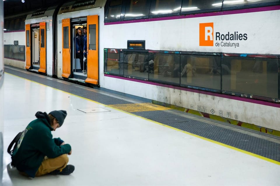A Rodalies R2 Sud train at a station platform, with passengers waiting or boarding.