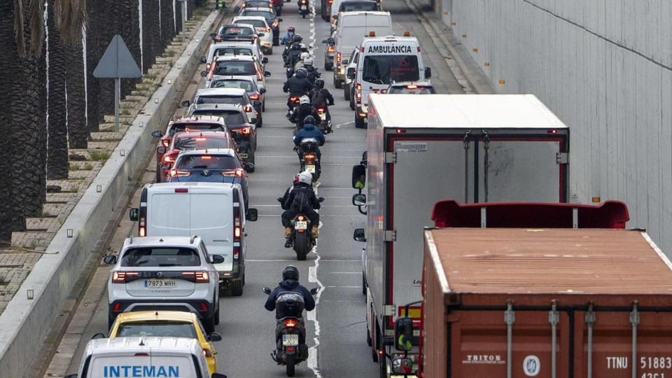 Aerial view of heavy traffic on a multi-lane motorway in Barcelona, with cars and lorries moving slowly.