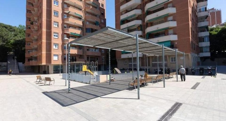 Newly renovated street in Barcelona's Can Baró neighbourhood with wide pavements and new paving, showing improved pedestrian 