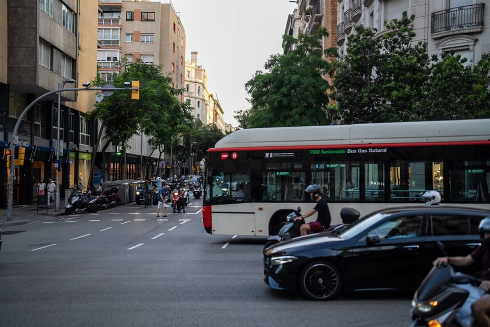 A white car with front-end damage after colliding with a red and white Transports Metropolitans de Barcelona (TMB) bus on a c