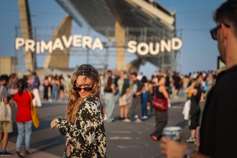 A large crowd of people enjoying a music festival at Parc del Fòrum in Barcelona, with a stage and lights in the background.
