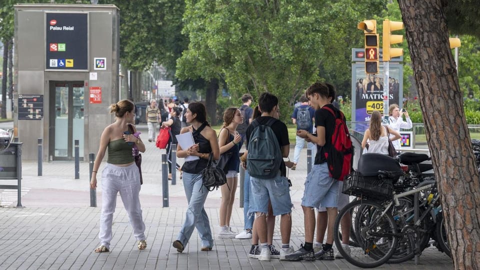 A busy street in Barcelona with a metro sign, showing traffic and pedestrians, representing transport disruption.