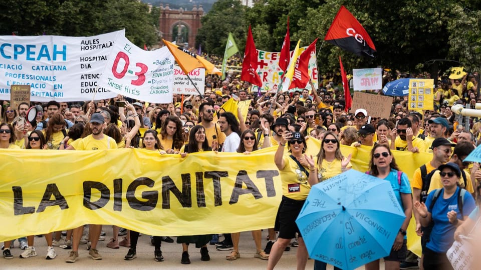 Protesters with banners blocking Avinguda Diagonal in Barcelona, with buses and cars visible in the background.