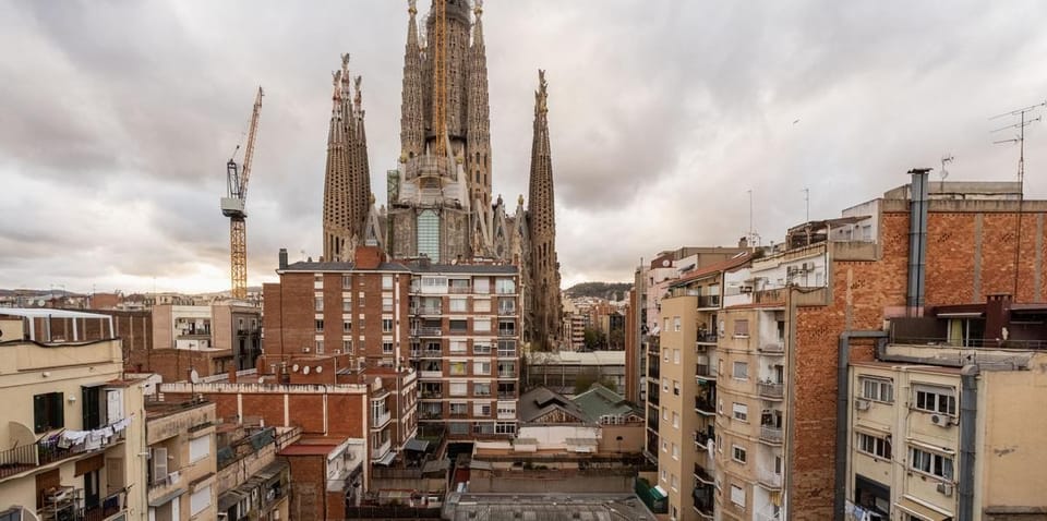 The unfinished Glory Façade of Sagrada Família basilica with surrounding residential buildings in Barcelona.