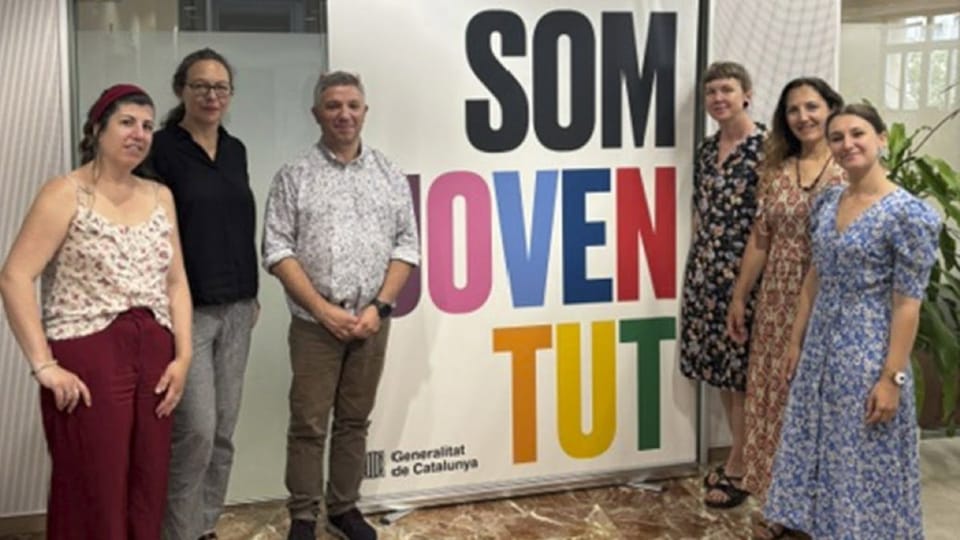 Five professionals from Strasbourg municipality meeting with Catalan Youth Agency representatives in a modern office setting.