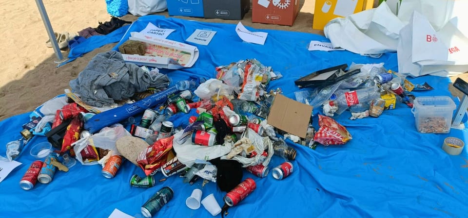 Volunteers collecting waste and cigarette butts on Barceloneta beach during a clean-up event.
