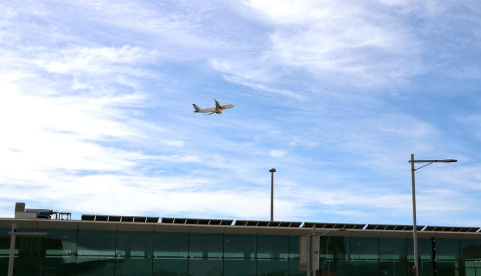 Barcelona-El Prat Josep Tarradellas Airport terminal building with planes on the tarmac and mountains in the background