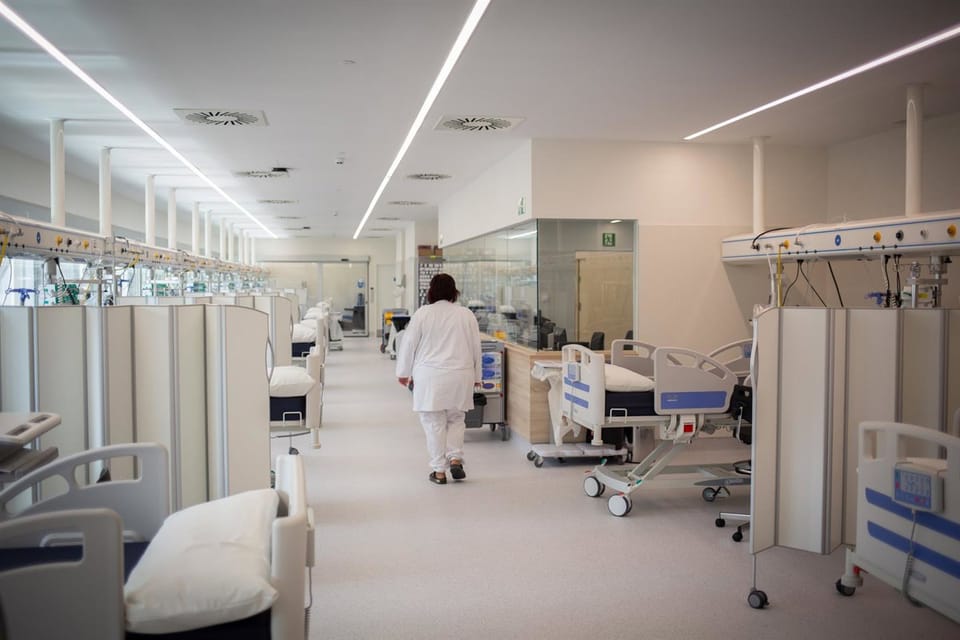 Doctor using a tablet to complete a digital form in a hospital setting.