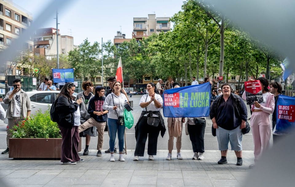 Exterior view of public housing blocks in La Mina, Sant Adrià de Besòs, with residents gathered outside.