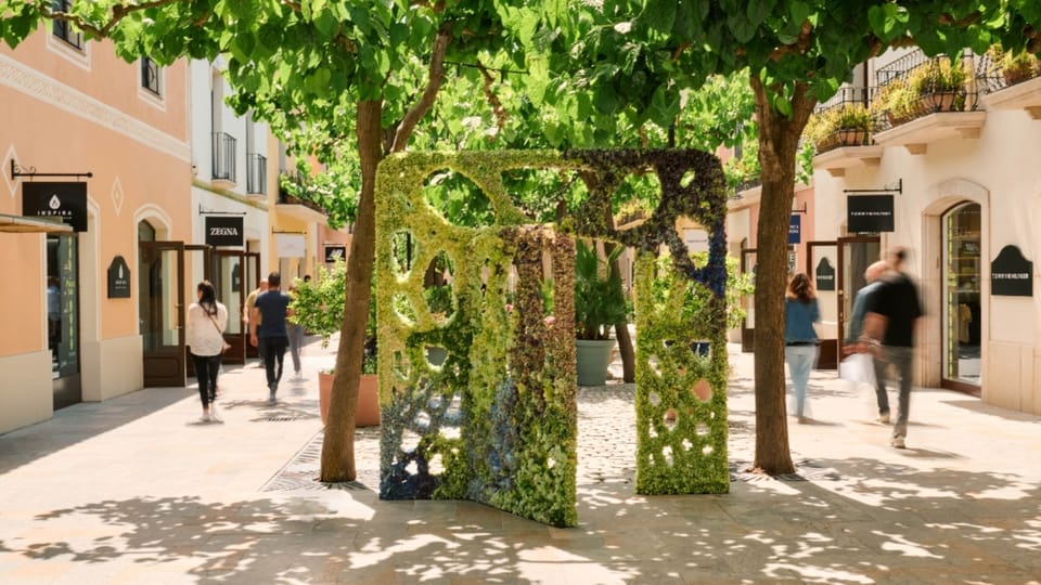 Three large, ornate floral doors inspired by Antoni Gaudí's architecture, set within an outdoor shopping village.