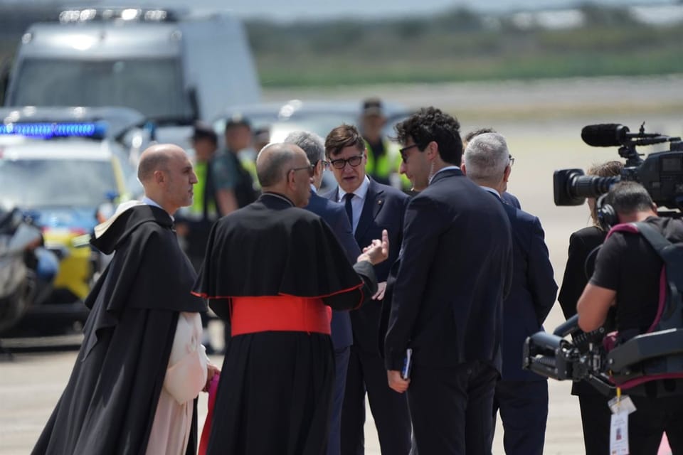 Pope Leo XIV walking on a red carpet after disembarking an Iberia plane at Barcelona-El Prat Airport, greeted by a line of of