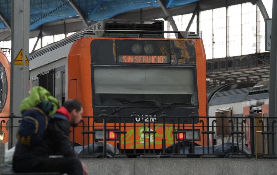 A Rodalies train arriving at a station platform in Barcelona, with passengers waiting to board.