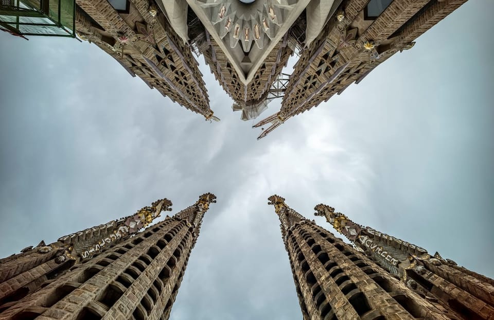 Sagrada Familia's Jesus tower with a large cross, rising above the Barcelona skyline.